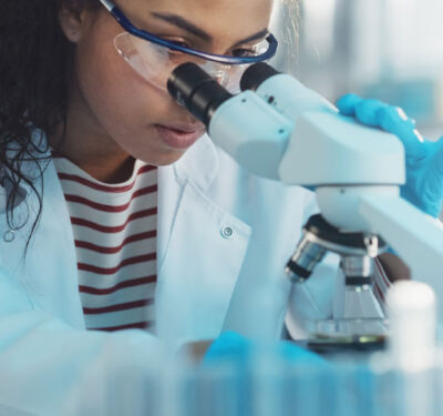Research-Fellows Young woman looking int a microscope.